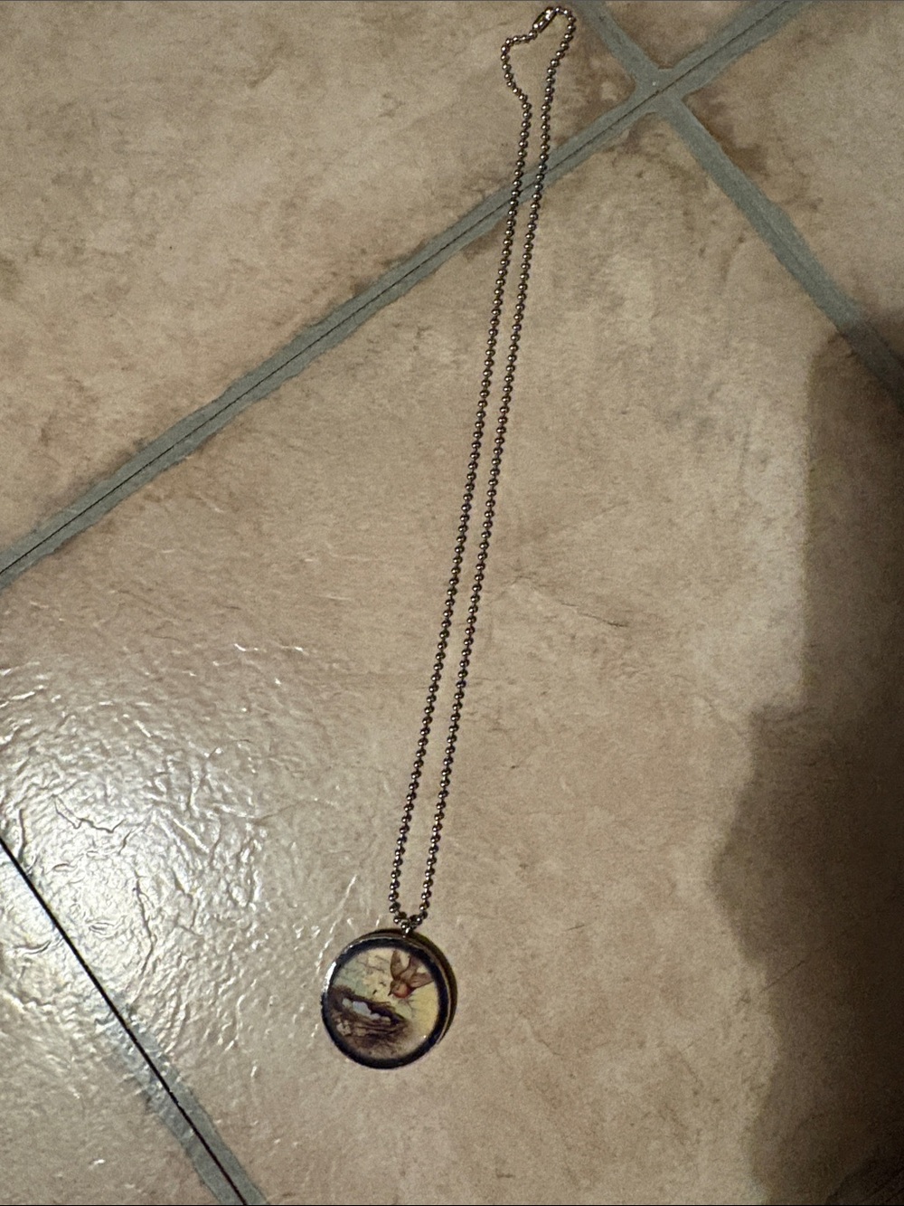Vintage-Style Gold Tone Pendant Necklace with Beige Illustration on wood.